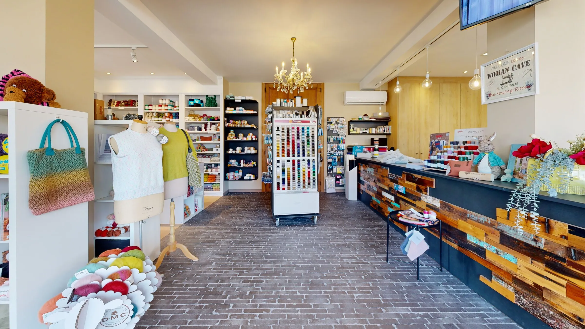 De winkel van Cortina met wol van DMC en Katia, gebreide truien op paspoppen en een kast vol garen